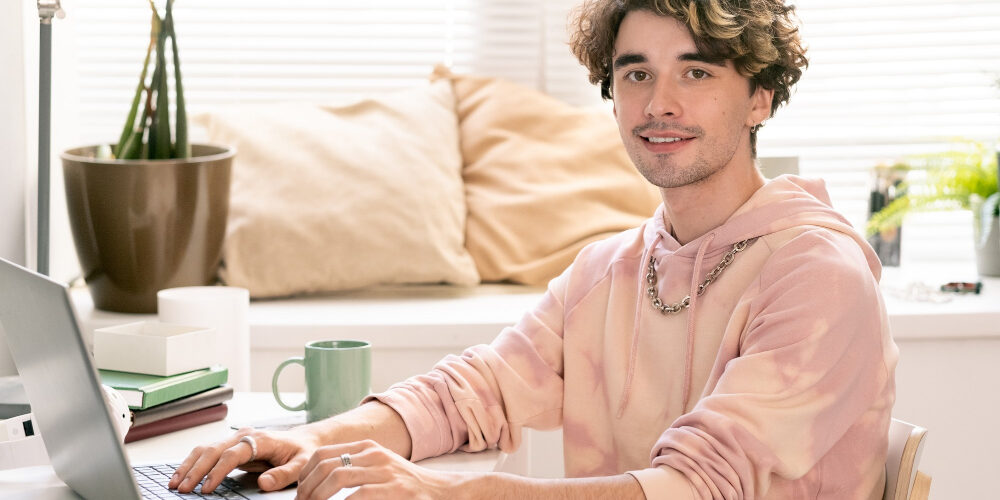 happy-teenager-with-laptop-looking-camera-with-smile