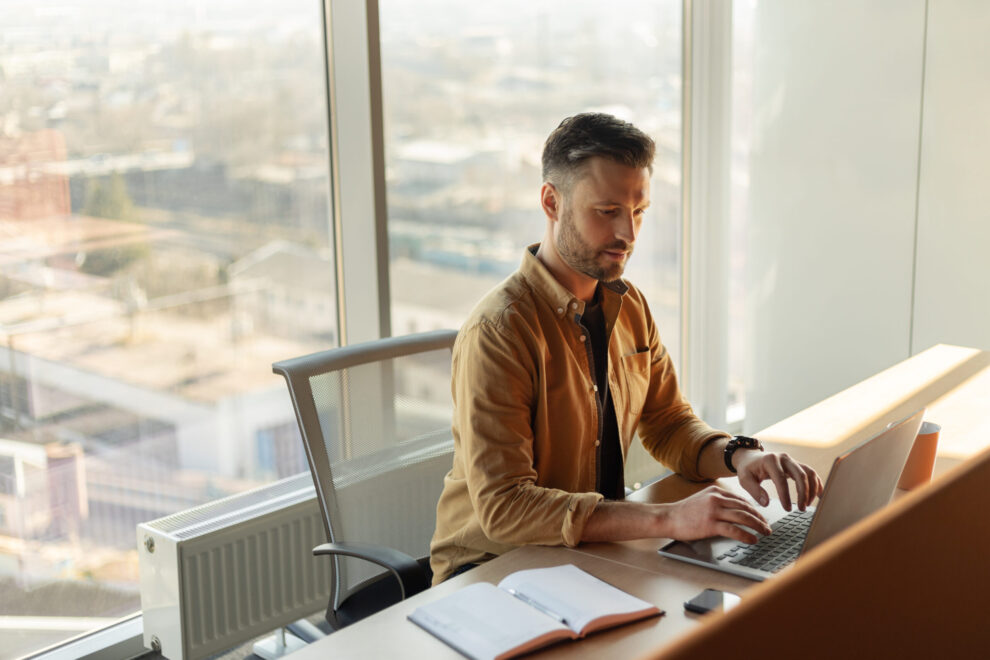 Side View Of Businessman Using Laptop Working Online In Office